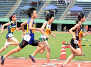 女子１年１００㍍。２位でゴールする朝日の幾（写真手前）＝２０日、県立鴨池陸上競技場