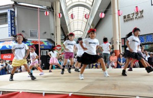 通行人が見守る中、商店街の特設舞台でダンスを踊る子どもたち＝１６日、奄美市名瀬