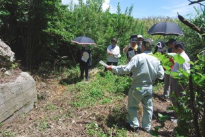 〇四艇格納庫の前で説明を受ける参加者ら＝２４日、喜界町白水