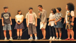 石田さん（中央）とやり取りする出演者の中高生５人＝１６日、奄美文化センター