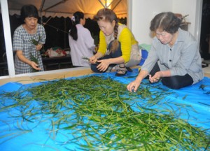 地域住民が「ヒヨヒヨ」と唱えながら投げ入れたソテツ葉を束ねる女性たち＝３０日午前５時５０分、瀬戸内町の清水集落