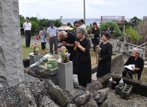 慰霊碑に献花して犠牲者の冥福を祈る参加者ら＝２３日、徳之島町