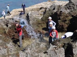 岩に海水をたたきつける汐干し体験をする児童ら＝４日、和泊町国頭の海岸