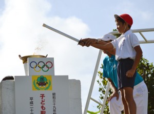 聖火台に火をともす秋和君＝２８日、和泊町の国頭小学校（同校提供）