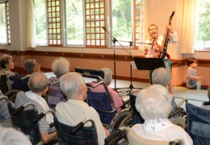 バンドゥーラの響きと澄み切った歌声でお年寄りを魅了したカテリーナさん＝２７日、奄美市