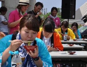 「わんこそば大会」で懸命にクワそばを頬張る参加者＝１３日、知名町のメントマリ公園