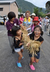 地域の子どもたちと一緒に綱引きを体験するツアー参加者＝８日、奄美市住用町西仲間