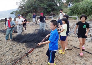 見張り台の合図を受け、網を引き上げる小中学生のモニター体験者たち＝１８日、宇検村芦検