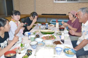 宿泊先の民家で夕食を囲み、楽しそうに会話する修学旅行生（左）＝２０日、与論町