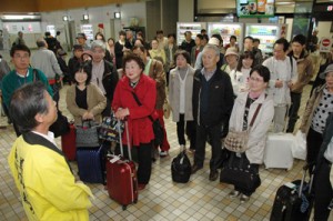 奄美大島に到着し歓迎を受ける広島発のツアー客ら＝２１日、奄美空港