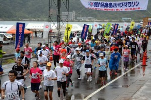 小雨の中、号砲とともに勢いよくコースに飛び出すハーフ出場者たち＝９日、瀬戸内町瀬相