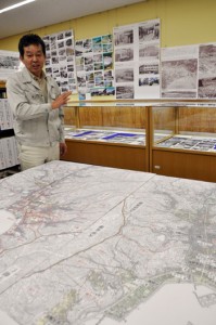 名瀬の歩みを振り返る写真と地図について説明する岩多さん＝９日、奄美図書館