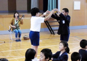 別府さんの島唄に合わせて手遊びする児童たち＝１９日、節田小学校