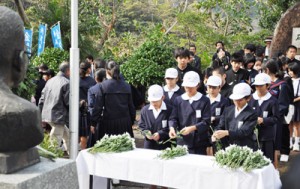 復帰運動の指導者・泉芳朗の胸像へ献花する児童生徒ら＝２５日、奄美市名瀬の「おがみ山公園」