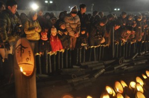 震災の犠牲者を悼み、竹灯篭のろうそくをともす人たち＝１７日午前５時４６分、神戸市中央区