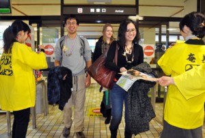 奄美空港に到着してシマ博のパンフレットを受け取る観光客＝３０日、奄美市笠利町