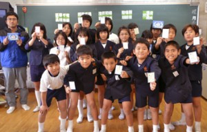 自分が描いたイラストのある札を持つ５年生と竹村さん（左）＝１６日、与論町の与論小学校