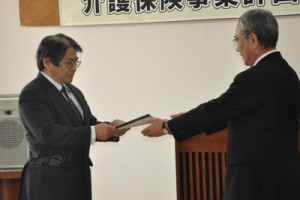 第６期計画を朝山市長に答申する稲委員長（左）＝１０日、奄美市役所
