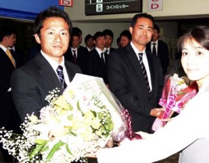 歓迎の花束を受け取る和嶋監督と渡邉貴美男主将（写真奥から）＝１３日、奄美空港