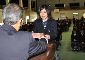 贈呈式で松田清藏理事長（左）から本を受け取る作南々帆さん＝２７日、徳之島高校
