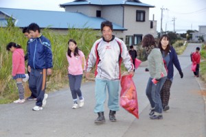 マラソンコース沿いのごみを拾う参加者＝２２日、与論島