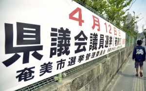 奄美市選管などが県道沿いに掲げた県議選の啓発横断幕＝２６日、奄美市名瀬塩浜町