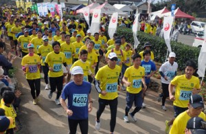 一斉にスタートするハーフ、ハーフリレーの参加者＝１５日、和泊町の笠石海浜公園