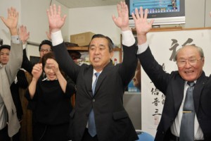 トップ当選を決め支援者らと万歳三唱する永井章義氏＝１２日午後１０時０８分、奄美市名瀬井根町