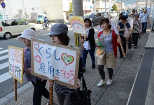 平和や労働者の権利などを訴えながらデモ行進する参加者＝１日、奄美市