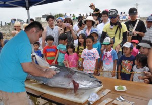 マグロの解体ショーに見入る来場者＝５月３１日、知名町の屋子母海岸