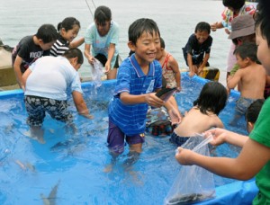 「グルクンのつかみ取り」で楽しそうに魚を追い掛ける子どもたち＝１９日、沖永良部島漁協