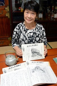 元明盛さんが戦後までを詳細にまとめた生涯日記を手にする長女の碩八重子さん＝１３日、奄美市名瀬