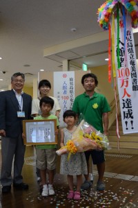 入館者１００万人目となった宮崎陽斗君家族と新宮領館長（左）＝３１日午後３時すぎ、県立奄美図書館