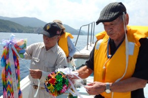 千羽鶴などを海に浮かべて対馬丸犠牲者を弔った上原さん（右）＝５日、宇検村船越海岸沖