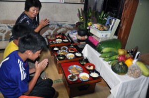 昔ながらの膳を先祖に供え、孫たちと手を合わせる東なつえさん（奥）＝１３日、知名町瀬利覚