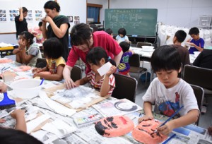 真剣な表情で仮面に色を塗る子どもたち＝６日、瀬戸内町立図書館・郷土館