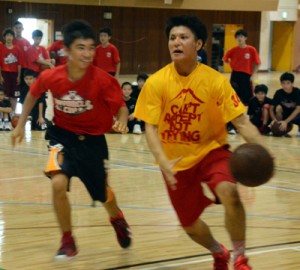 鮫島選手（右）とマンツーマンでボールを奪い合う中学生＝１７日、名瀬総合体育館