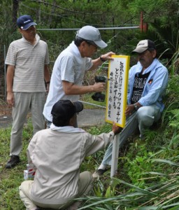 アマミノクロウサギの交通事故防止を啓発する看板を設置するＮＰＯ法人徳之島虹の会のメンバーら＝８日、徳之島町