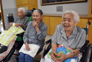 記念品の贈呈式で笑顔を見せる（右から）春山さんと加島さん＝１５日、喜界町赤連の喜界園