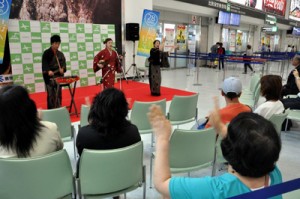 鹿児島空港国内線ビル出発ロビーで島唄を披露する澤愛香さんと「つむぎんちゅ」の２人＝５日、霧島市溝辺麓