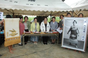 篠川集落に化粧回し（左）を贈った琉王の遺族（正面の女性４人）ら＝２０日、瀬戸内町篠川 