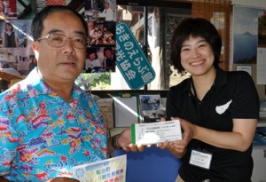 発売された「めんしょり観光振興券」を購入する島民（左）＝１日、和泊町のおきのえらぶ島観光協会案内所
