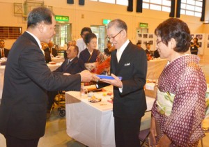 結婚から５０年の節目を祝い、伊集院村長から記念品が贈られた大和村の合同金婚式＝２５日、同村体育館