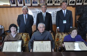 （前列右から）総務大臣表彰を受けた岩崎さんと同感謝状を受けた名島さん、伊集院さん＝２１日、奄美市役所