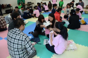 協力して赤ちゃんの着替えを体験する参加者＝１９日、奄美市