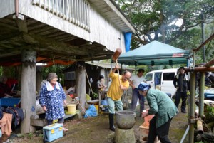 高倉の前で餅つきを楽しむ人たち＝２７日、龍郷町