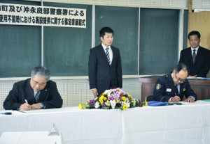 協定書に署名する伊地知町長（左）と松元署長ら＝１４日、沖永良部署