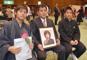 雅恵さんの遺影を手に成人式に参列した稲井さん家族（左から啓大さん、均さん、駿君）＝４日、瀬戸内町