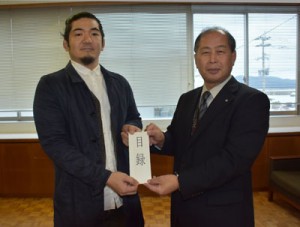 新築住宅助成金の目録を手にする吉見さん（左）と鎌田町長＝２日、瀬戸内町役場