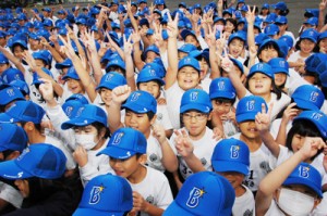 ベイスターズから届いた野球帽をかぶり笑顔の児童ら＝３日、奄美市の朝日小学校